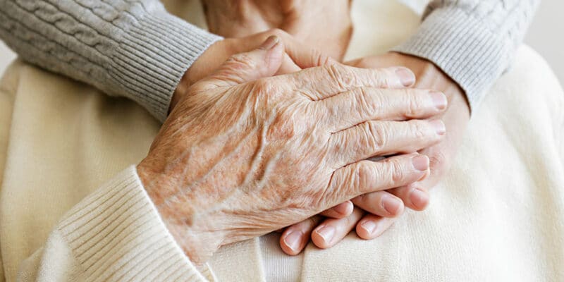 Senior hands clasping together over heart